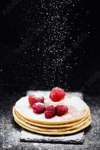 Pancakes with berries and sugar on dark background photo