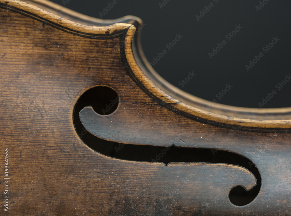 part of violin with f hole against grey background part of violin with f hole against grey background