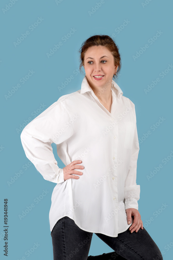Portrait of the beautiful mature adult woman in a white blouse of the blond brown hairdo on blue background with copy space. Portrait of the beautiful mature adult woman in a white blouse of the blond brown hairdo on blue background with copy space.