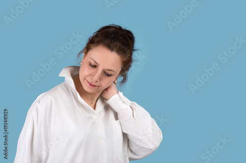 Portrait of the beautiful mature adult woman in a white blouse of the blond brown hairdo on blue background with copy space.