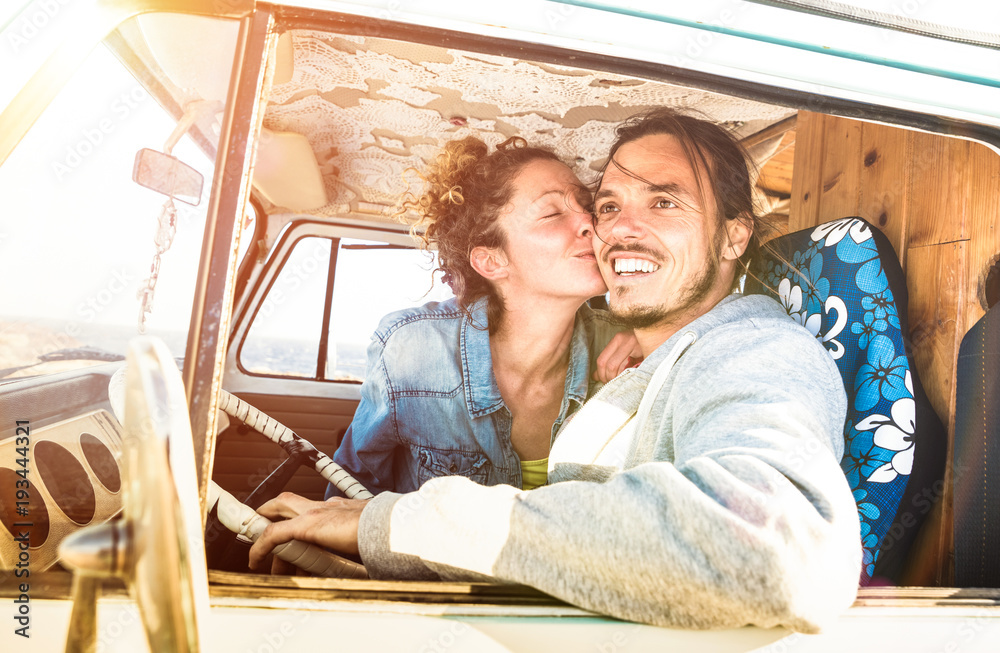 Hipster couple ready for roadtrip on oldtimer mini van transport - Travel lifetstyle concept with indie people kissing on minivan adventure trip having fun in relax moment - Warm bright filter Hipster couple ready for roadtrip on oldtimer mini van transport - Travel lifetstyle concept with indie people kissing on minivan adventure trip having fun in relax moment - Warm bright filter