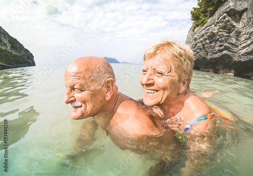 Senior couple vacationer having genuine playful fun on tropical beach in Thailand - Snorkel tour in exotic scenario - Active elderly and travel concept around the world - Warm afternoon bright filter © Mirko Vitali