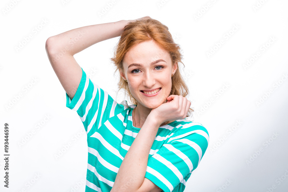 Close-up portrait of a young, beautiful woman with red curly hair in a summer dress with strips of blue in the studio on a gray background. Theme of summer vacation, tourism and summer clothes Close-up portrait of a young, beautiful woman with red curly hair in a summer dress with strips of blue in the studio on a gray background. Theme of summer vacation, tourism and summer clothes