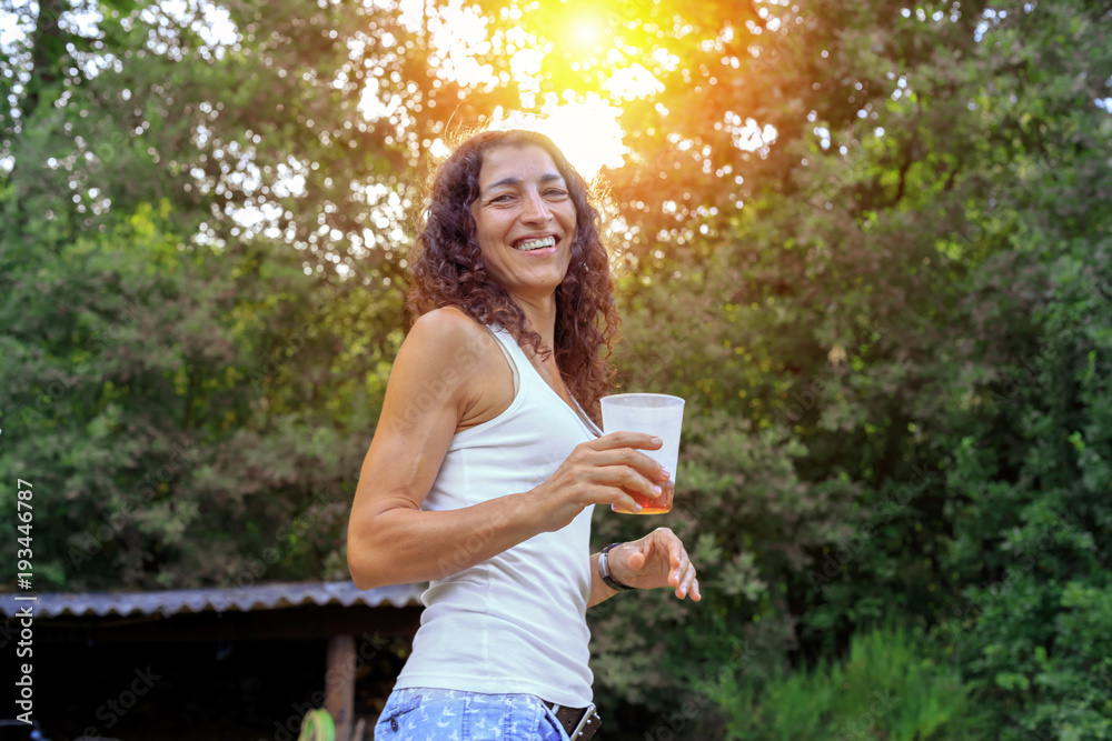Naklejka premium Beautiful young woman holding soda and smiling at summer. Summer joy concept.