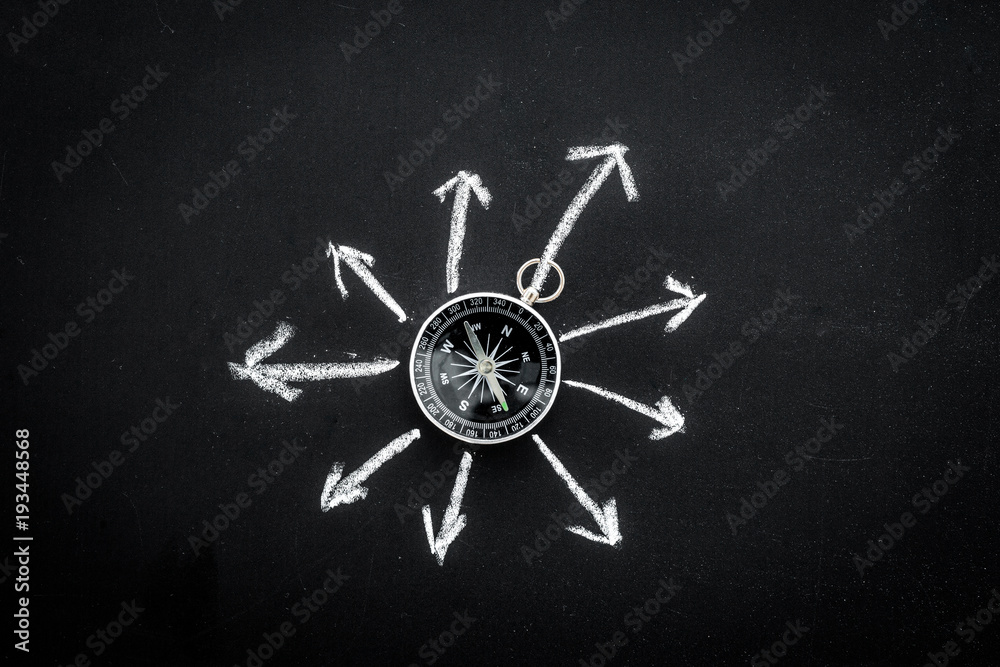 Direction of movement, travel direction. Compass among the arrows on black background top view copy space