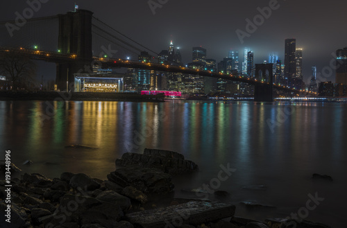 New York City Manhattan skyline and Brooklyn Bridge at night over Hudson River