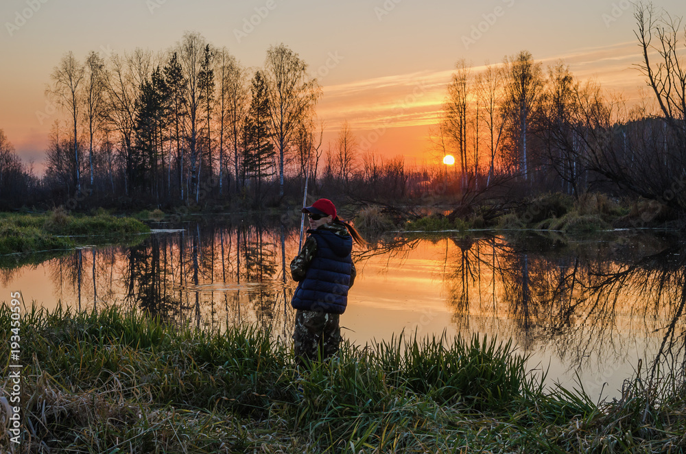 Obraz premium Woman fishing at sunset