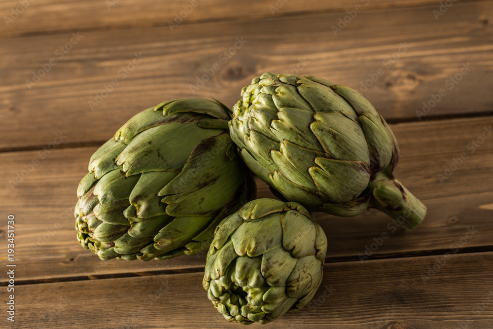 Fototapeta premium Natural artichokes on a rustic wooden table.
