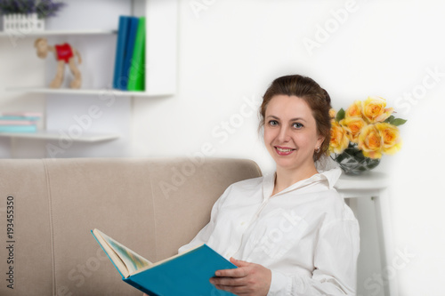 Portrait of the beautiful mature adult woman of the brunette on sofa in the room photo