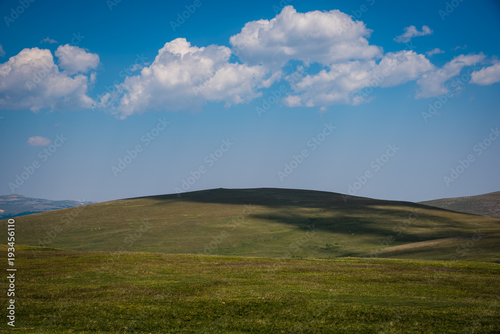 Fototapeta premium Blue sky puffy clouds and green hills