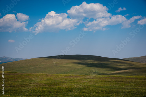 Blue sky puffy clouds and green hills