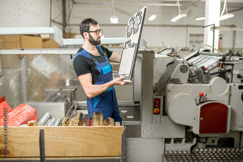 Worker standing with cliche for cutting boxes at the vintage printing manufacturing
