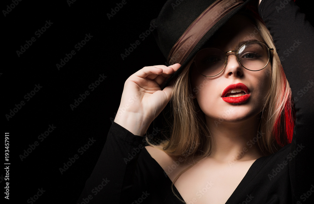 Sexy blonde woman wearing brown hat and glasses, posing at black background Sexy blonde woman wearing brown hat and glasses, posing at black background