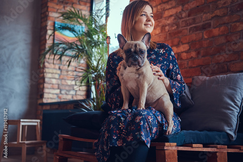 Portrait of a smiling woman sitting with a cute pug in a room wi © Fxquadro