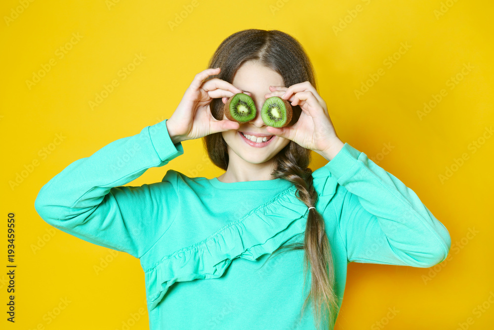 the girl with kiwi fruit on a yellow background the girl with kiwi fruit on a yellow background