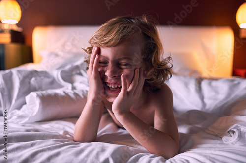 Happy boy lying in bed photo