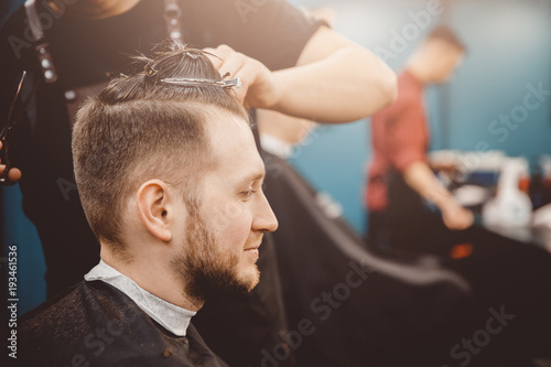 Barber master hairdresser does hairstyle and style with scissors and comb. Concept Barbershop.