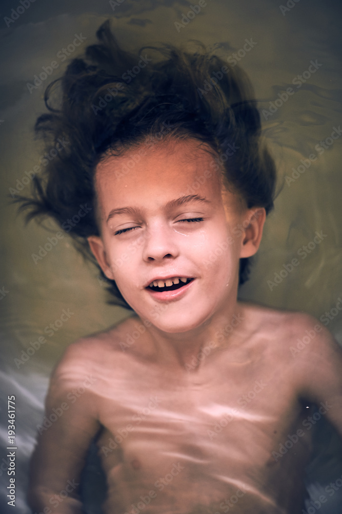 Cheerful boy lying in bath Cheerful boy lying in bath