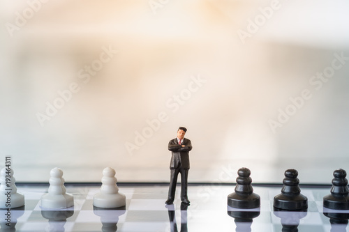 Business and Competition Concept. Businessman miniature figure standing on chessboard with black and white chess pieces