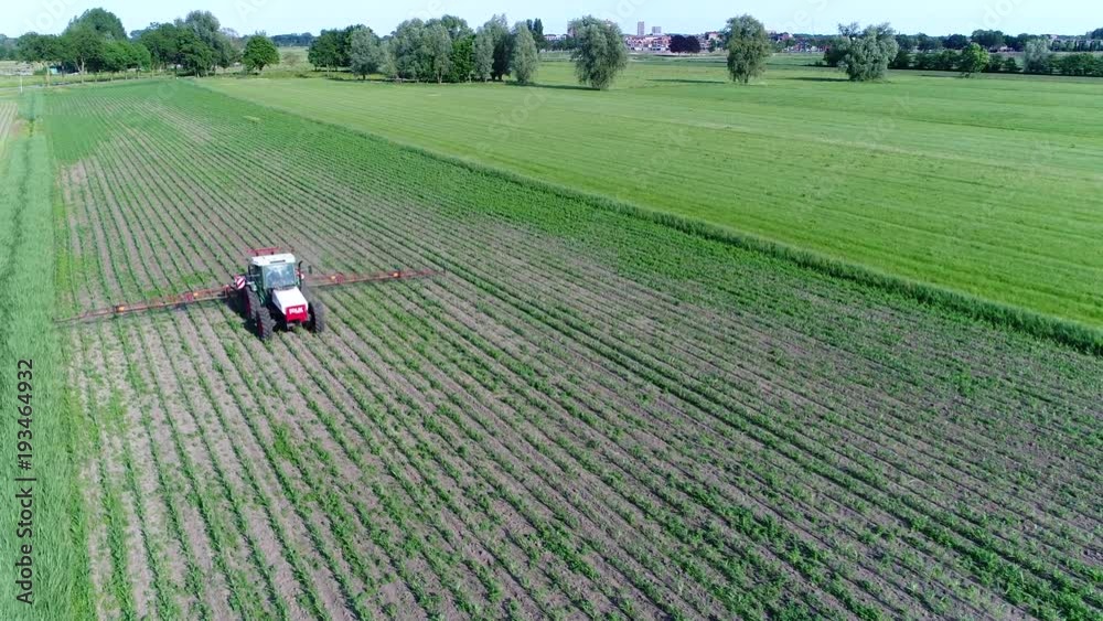 Aerial corn field and tractor spraying agrochemical or agrichemical over the young maize field in most cases agrichemical refers to pesticides like insecticides herbicides fungicides and nematicides Aerial corn field and tractor spraying agrochemical or agrichemical over the young maize field in most cases agrichemical refers to pesticides like insecticides herbicides fungicides and nematicides