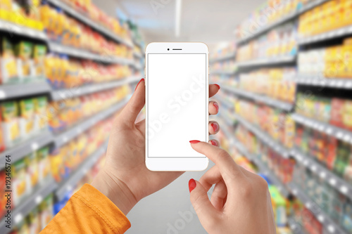 Female hand holding mobile smart phone with isolated white screen in supermarket