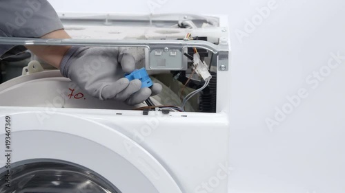 Taking apart the whole washing machine. A epairman is wearing safety gloves. photo