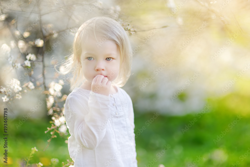 Adorable little girl in blooming cherry tree garden on beautiful spring day Adorable little girl in blooming cherry tree garden on beautiful spring day
