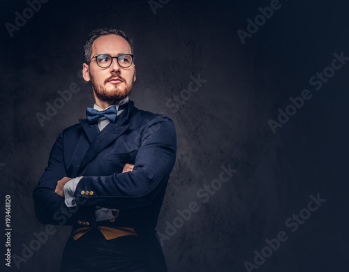 Portrait of a bearded male in glasses and antique suit on a dark