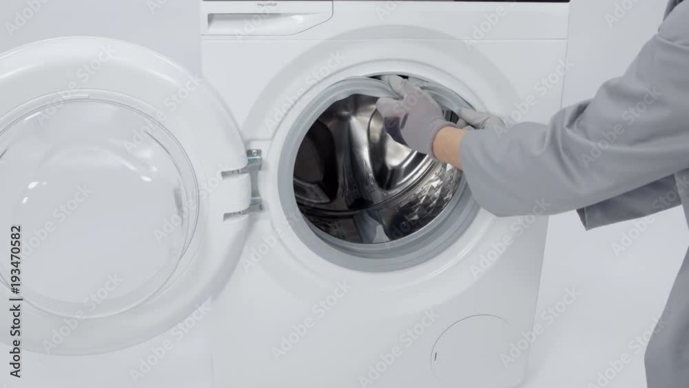 A man is taking out a washing machine rubber. He is going to fix the washing machine.