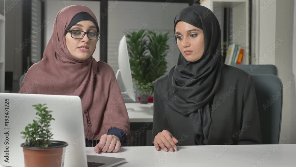Two beautiful young girls in hijabs sit in the office and discuss schedules, business, dialogue, conversation. 60 fps Two beautiful young girls in hijabs sit in the office and discuss schedules, business, dialogue, conversation. 60 fps