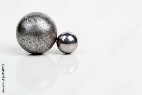 Две металлических сферы разных размеров изолированные на белом фоне. 