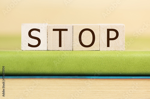 stop written in wooden cubes on a green book 