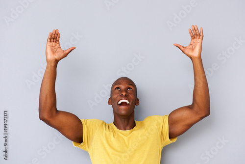 happy black man with arms and hands raised to lift photo
