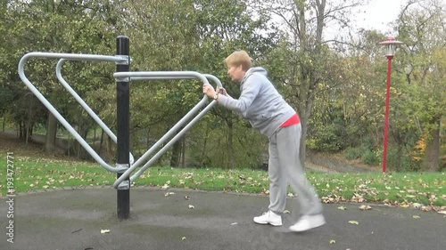 A woman does stretches – An old woman does stretches in an outside gym in one of the local parks, Newcastle upon Tyne, UK photo