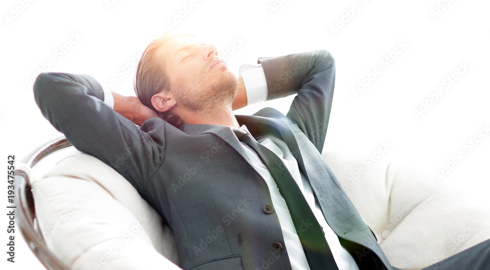 young businessman meditating in big comfortable armchair
