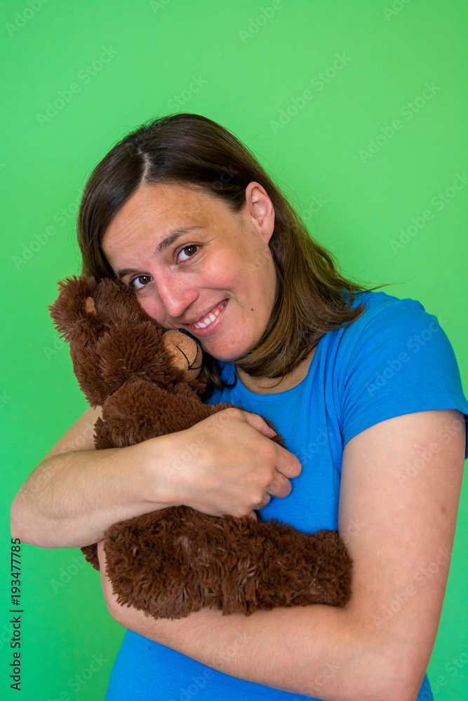 Pregnant woman posing with a plush toy imitating baby in front of green background. Pregnant woman posing with a plush toy imitating baby in front of green background.