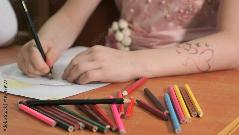 Close-up of unknown child draws the pictures using color pencils in the album in the kindergarten Close-up of unknown child draws the pictures using color pencils in the album in the kindergarten