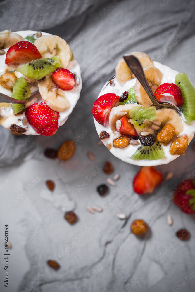 Obraz premium Nutrition Yoghurt fruit dessert strawberries banana kiwi raisins sunflower seeds oatmeal walnuts caramel