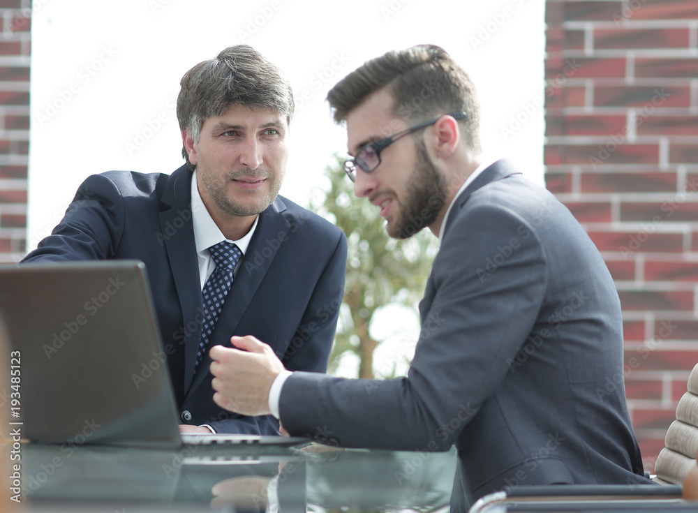 Two businessmen working together using laptop on business meeting in office Two businessmen working together using laptop on business meeting in office