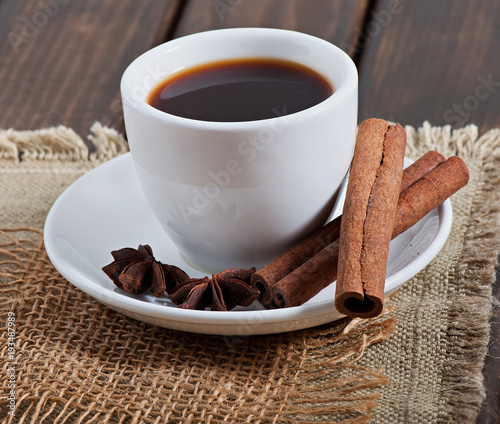 Cup of fragrant coffee and spices on an old wooden background.