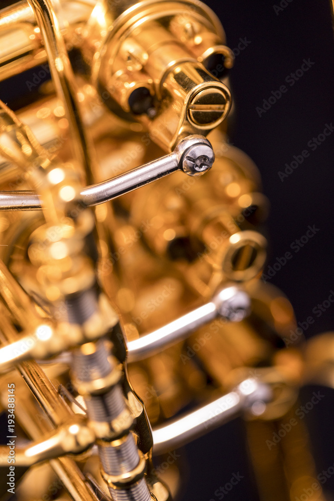 Fototapeta premium A part of a gold plated rotary trumpet on a black background