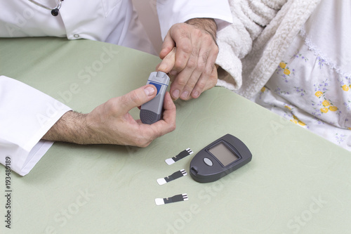 3. Lekarz diabetolog w białym fartuchu i okularach bada poziom cukru u bardzo starej siwej kobiety.