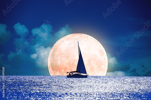 Silhouette of a boat with full Moon on the ocean. 
