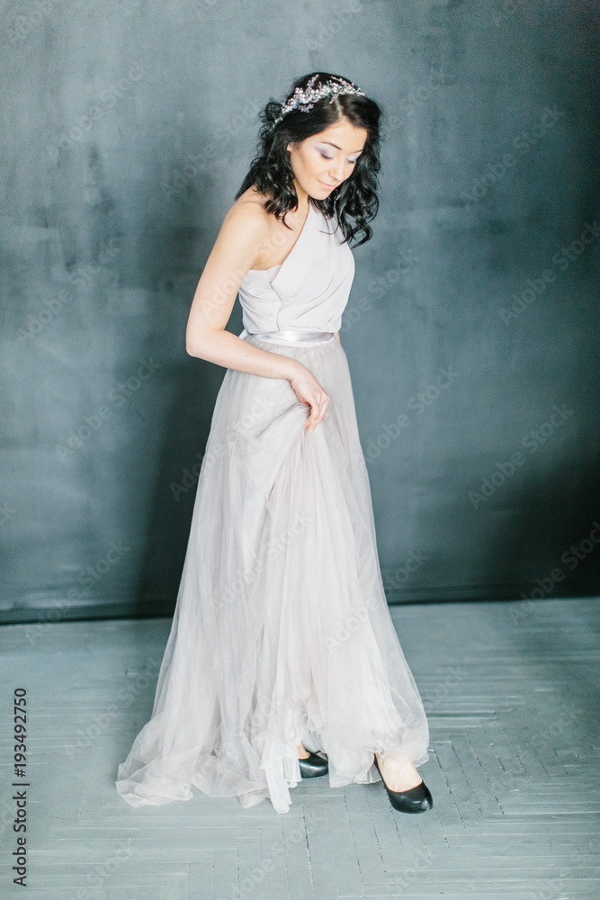 Young beautiful bride with a beautiful diadem in the hair poses standing on dark background. Young beautiful bride with a beautiful diadem in the hair poses standing on dark background.