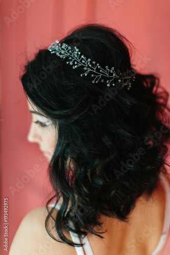 Young beautiful bride with a beautiful diadem in the hair poses standing on red background.