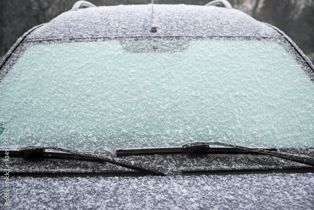 Obraz premium frozen windshield of a car with ice and snow, concept of traffic risks in winter, copy space