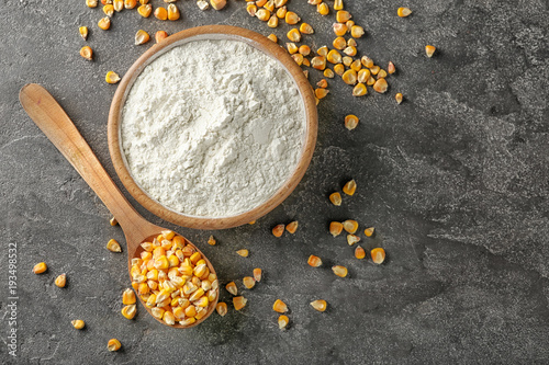 Spoon with kernels and corn starch in bowl on table photo
