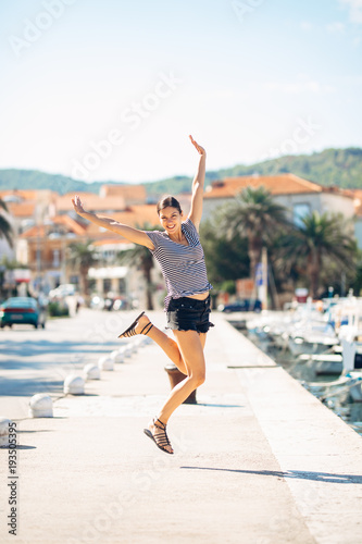 Fototapeta Naklejka Na Ścianę i Meble -  Over exited happy woman jumping in the air out of happiness.Vacation time concept.Seaside coastal vacation excitement.Woman in joy got good news.Rejoicing,full of life.Summer female active,energetic