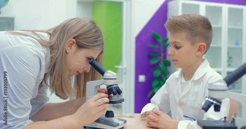 Teacher helps students to adjust the laboratory microscope to work Teacher helps students to adjust the laboratory microscope to work