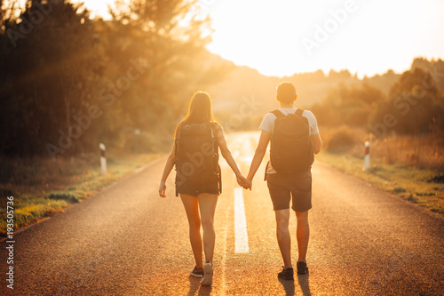 Young backpacking adventurous couple hitchhiking on the road.Adventure of life.Travel lifestyle.Low budget traveling.Adventurous active vacations.Hitchhiking tourism concept.Backpackers together